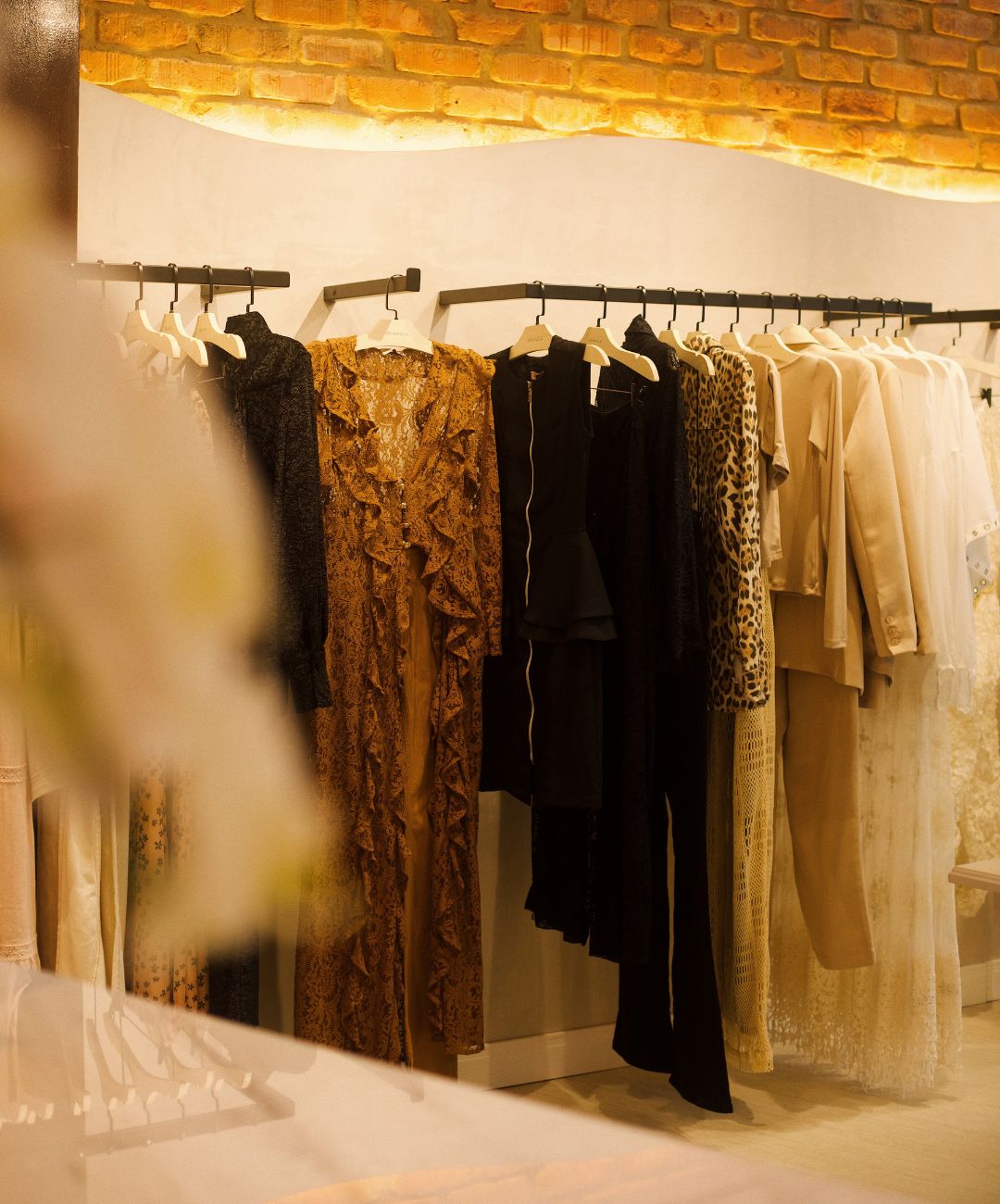 Arara de roupas femininas Branca Boutique com peças em tons quentes e neutros no evento Coffee Itaipava