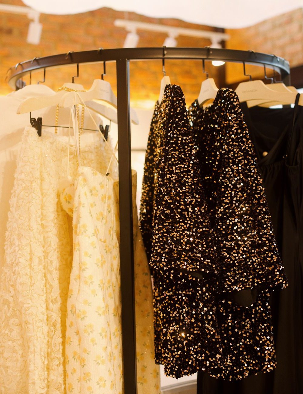 Arara circular com vestidos de renda creme e vestidos pretos com paetrê no evento Branca Boutique Coffee Itaipava