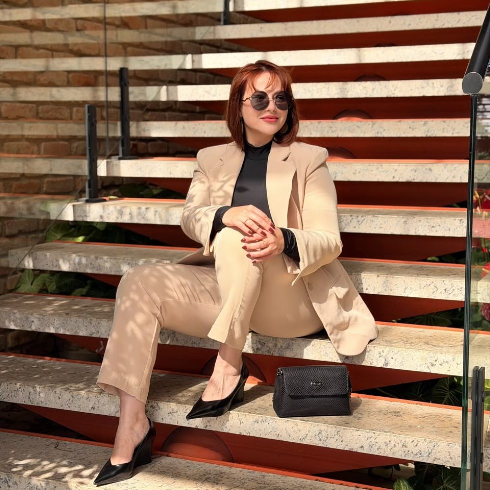 Fundadora Sunamita Branca Boutique sentada escadaria tailleur bege look elegante óculos de sol Nossa Curadoria moda feminina