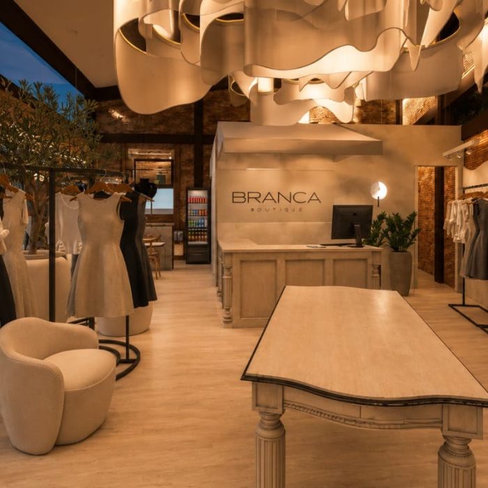 Interior projeto loja Branca Boutique Itaipava Petrópolis decoração teto orgânico araras roupas mesa central ambiente luxuoso